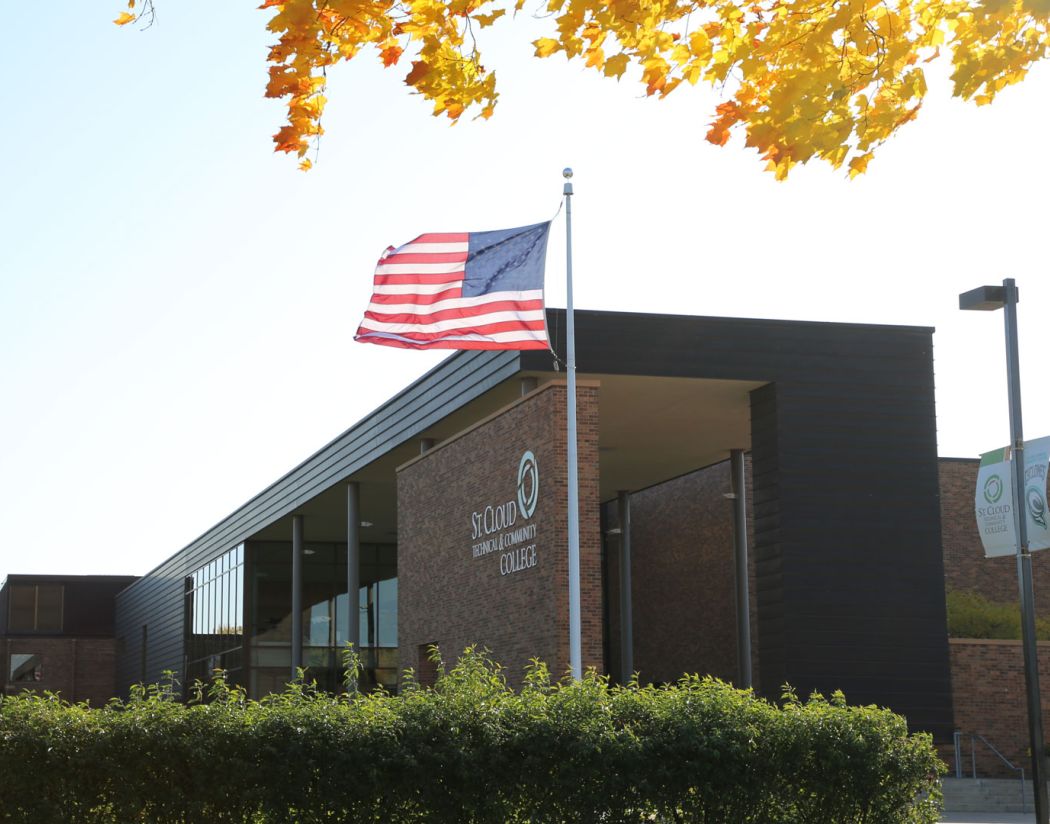 SCTCC main entrance with flag blowing in wind and yellow leaves at edge of image 
