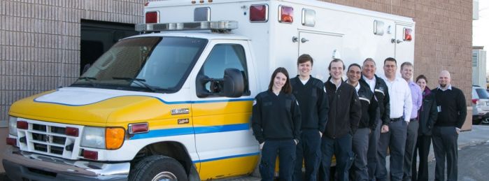 group of paramedicine student standing in front of white and yellow ambulance
