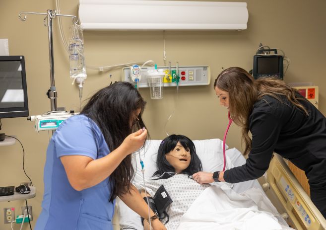 two nursing students working with a Training Mannequin