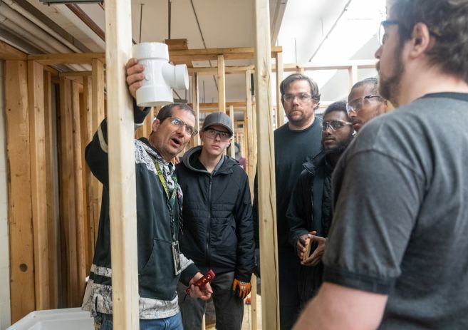 students listening as instructor explains placement of plumbing joint