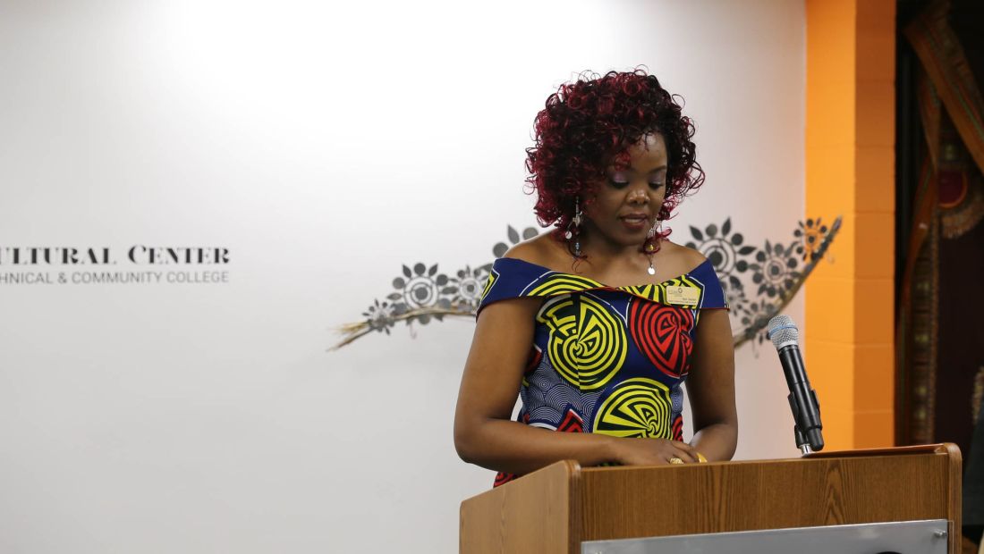 Njeri, a black woman, speaking at a podium