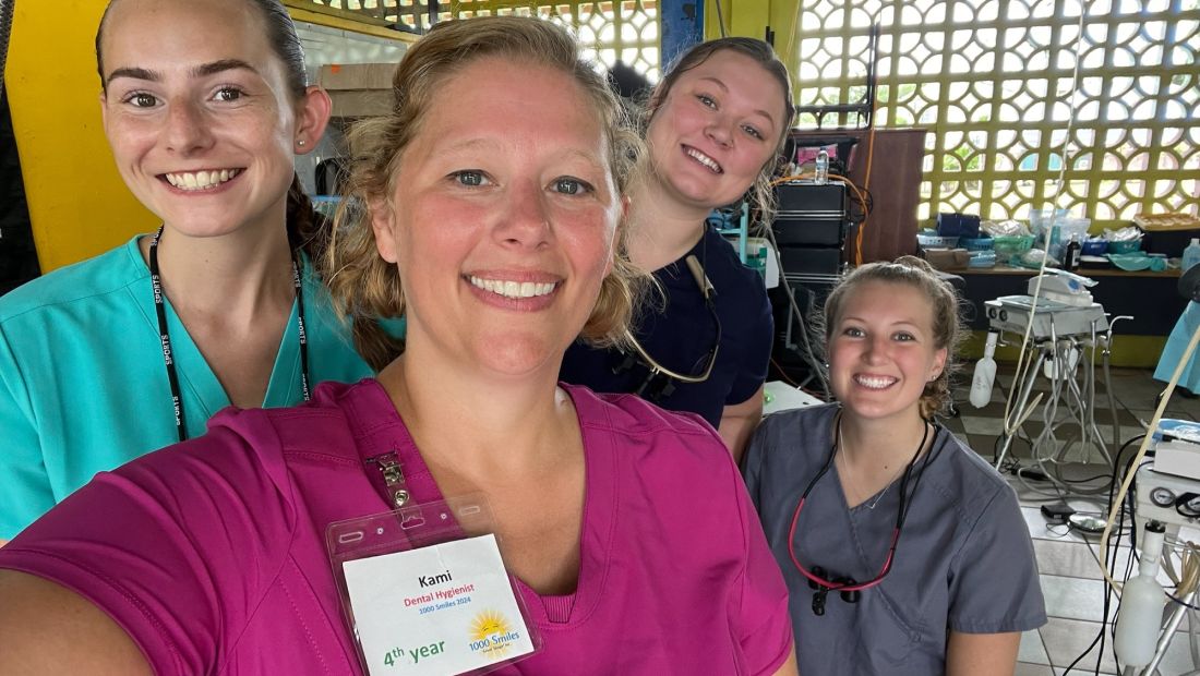 Four volunteer women in scrubs smiling at camera