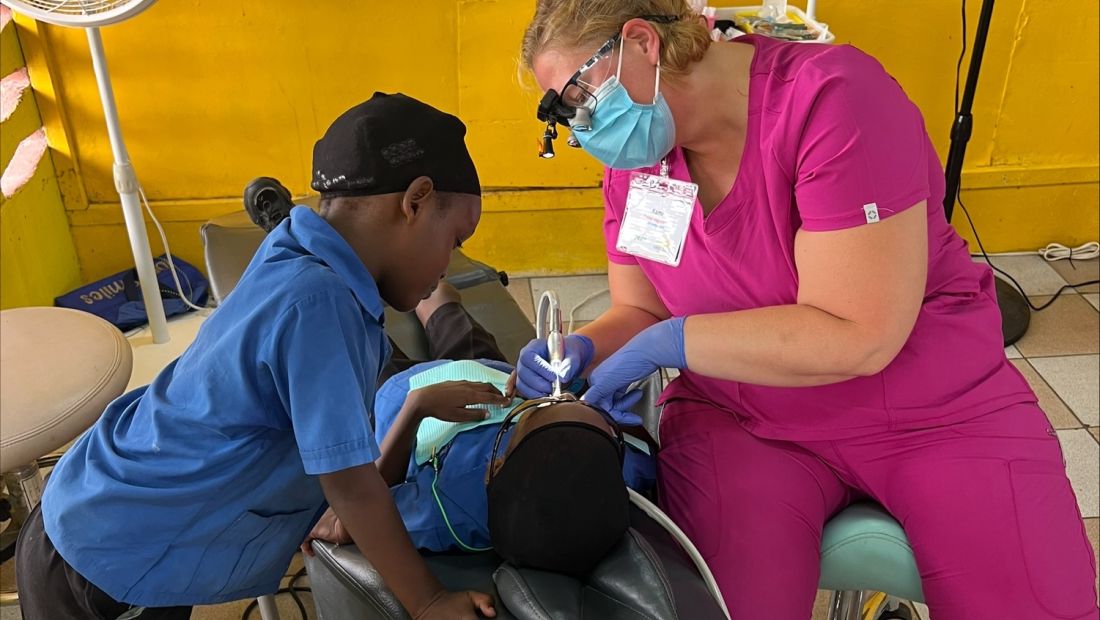 Kami in pink scrubs helping with dental procedure