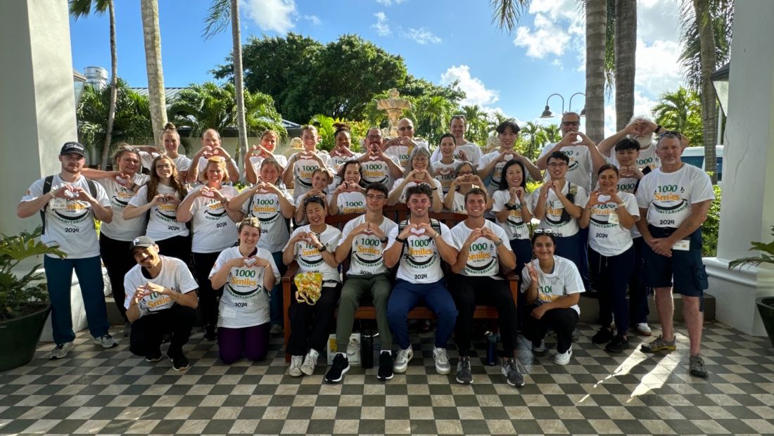 Large Group of volunteers with heart hands smiling at camera outdoors