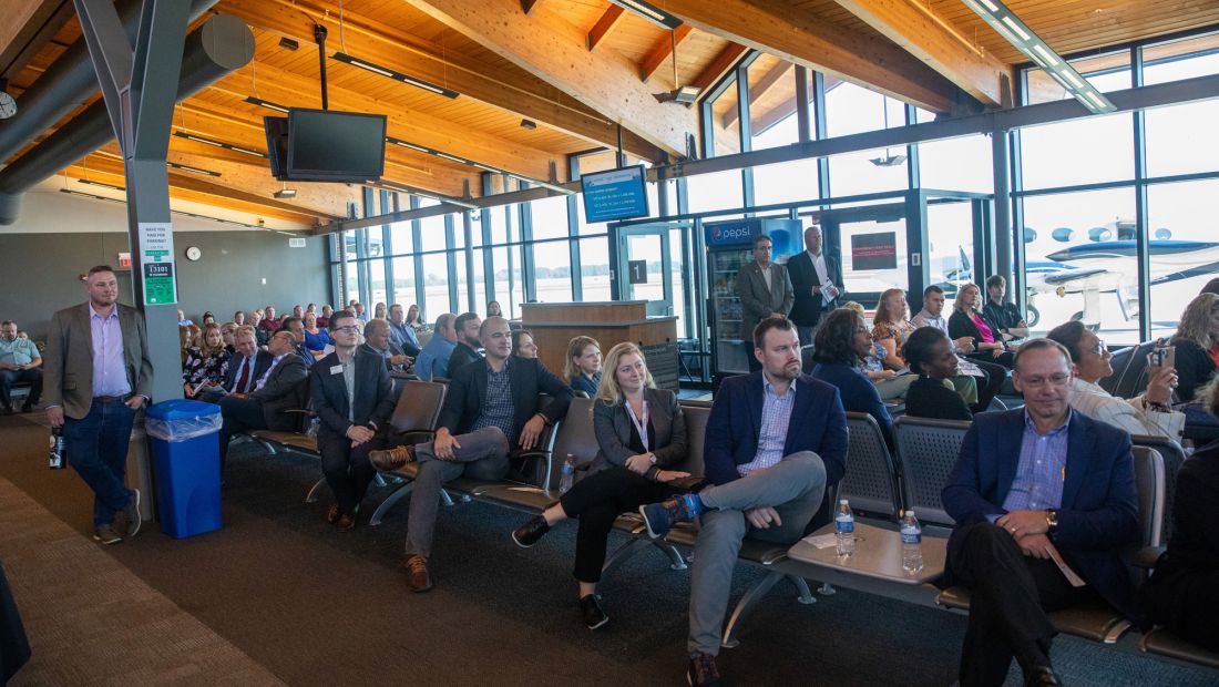 Audience sitting in the terminal at St. Cloud Airport listening to speakers at event