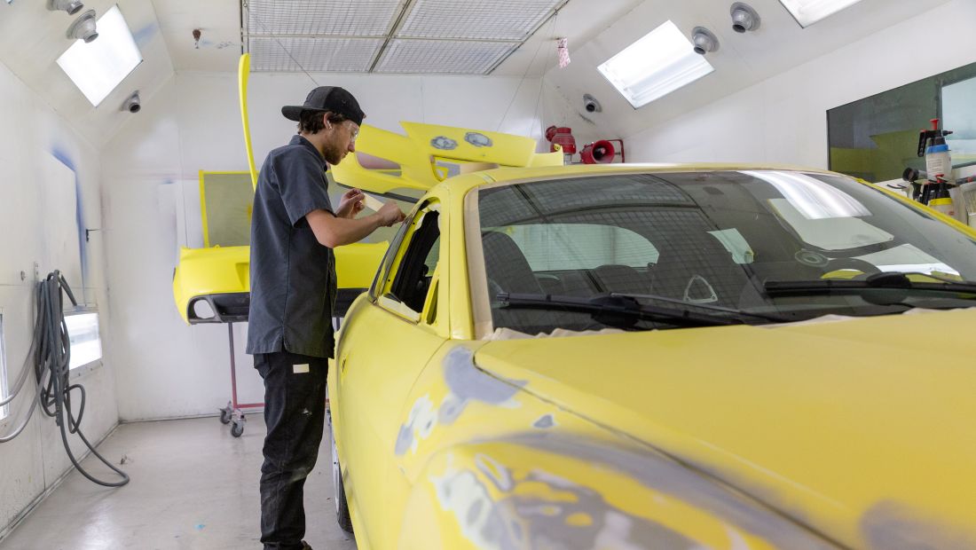 student taping off car in prep for paint
