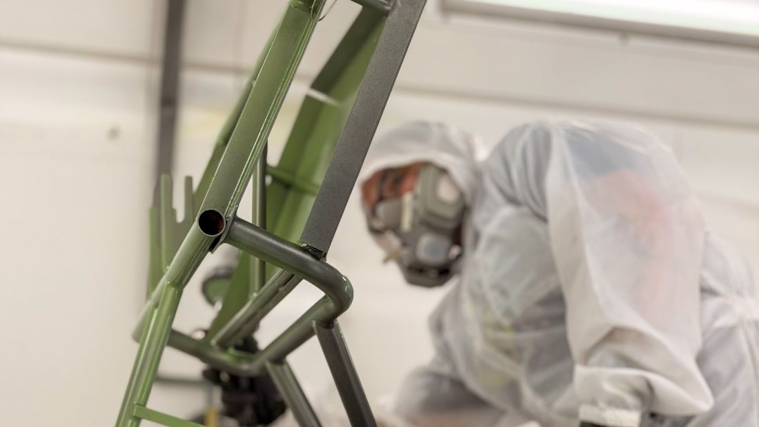 bike being painted, person in full paint suit in background