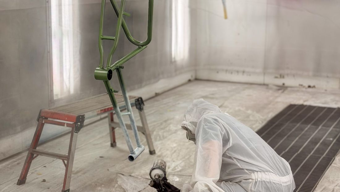 bike being painted, person in full paint suit in background