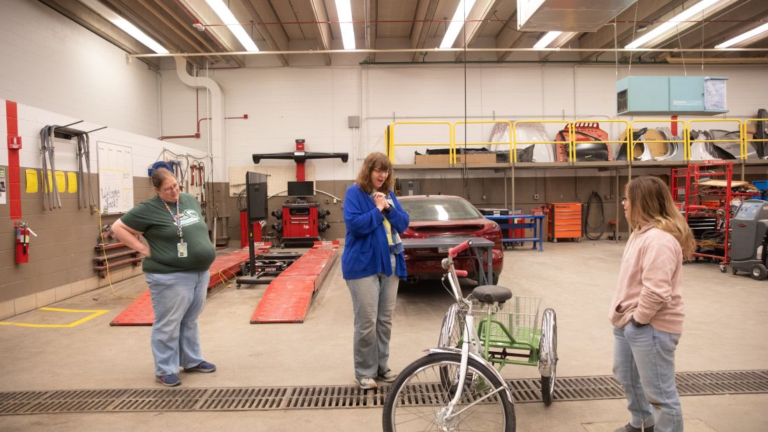 Mary sees bike for the first time inside the auto body lab