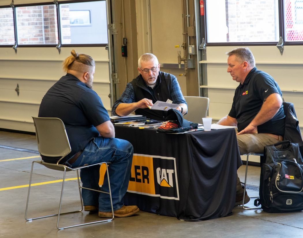 student interviews at table with two employers
