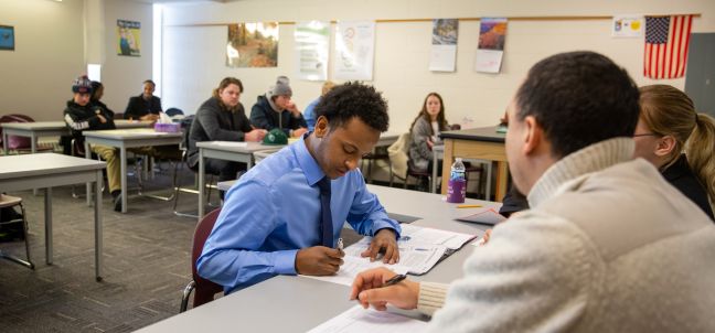 group of students at table, looking at information on papers