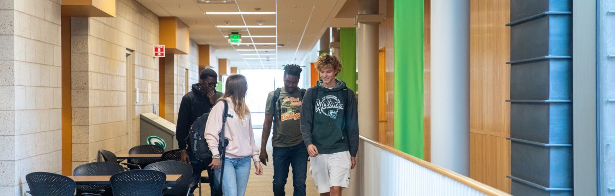 group of 4 students with backpacks, wearing SCTCC shirts and sweatshirts walking in a hallway