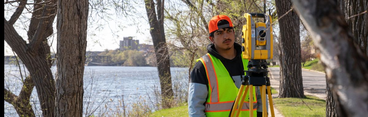 student at a river, framed by trees, surveying