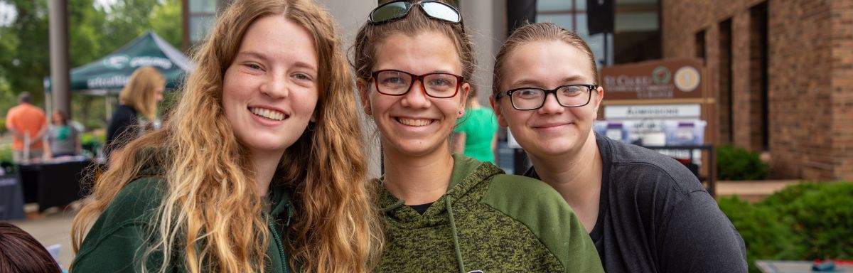 three women in green shirts smile at camera