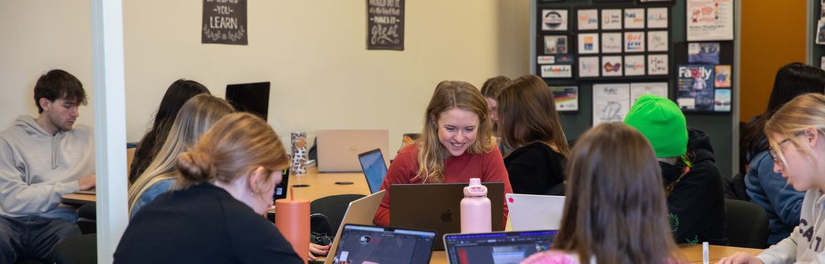 students in classroom, working on computers with designs in background