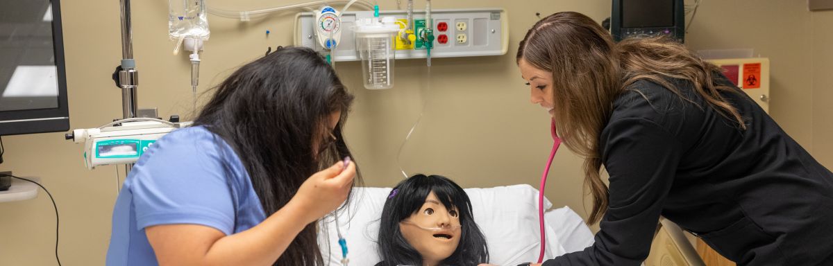two nursing students working with a Training Mannequin
