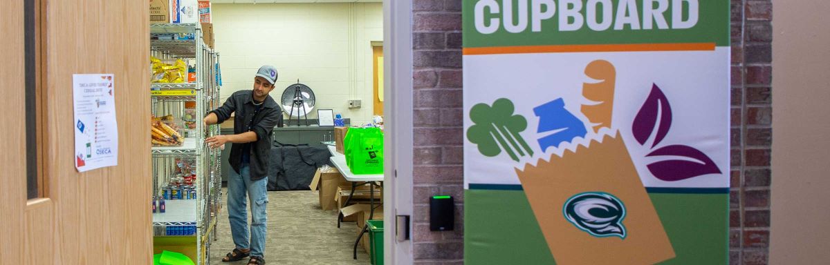 A student worker puts food on shelves in the cupboard