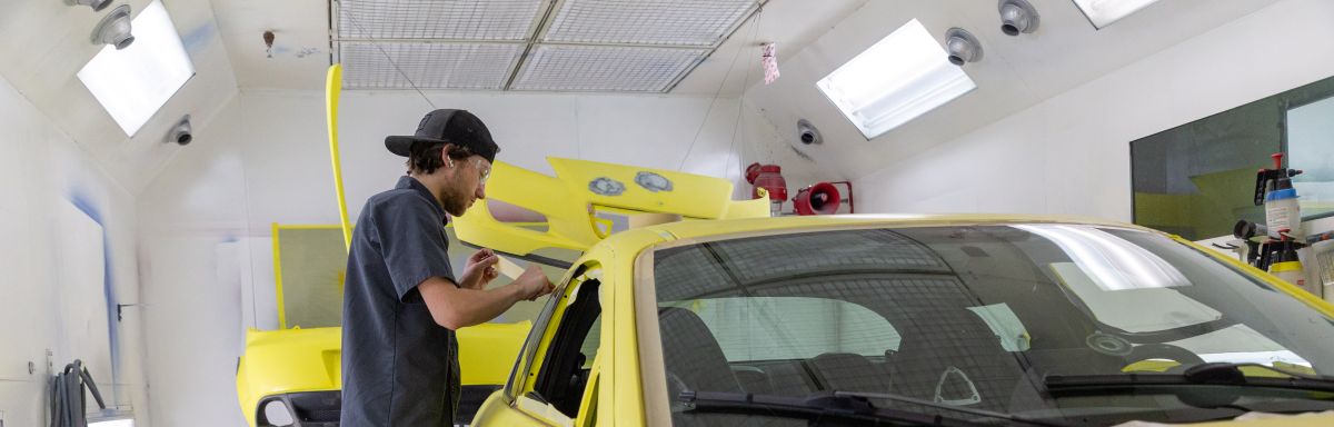 student taping off car in prep for paint