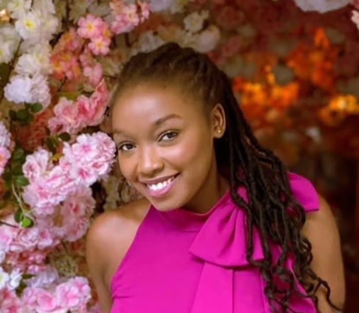 Tourpah in pink dress in front of floral background