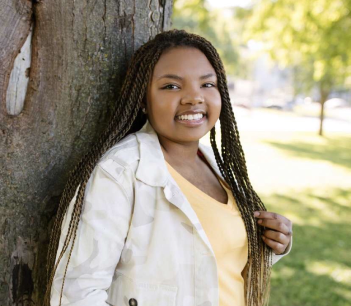 Nia outside by a tree smiling at camera