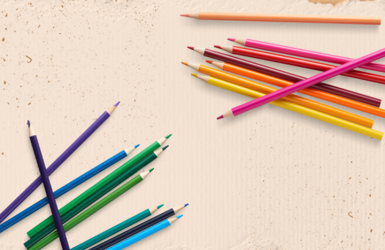 Image of paper background and different colors of colored pencils laying on the paper.