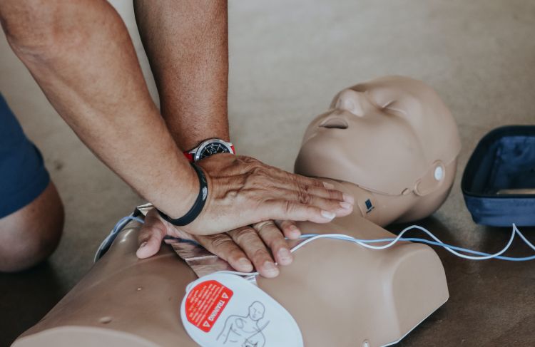 person applying chest compressions to CPR manikin