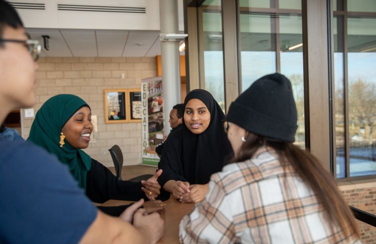 trio students talking while at a table near door 1
