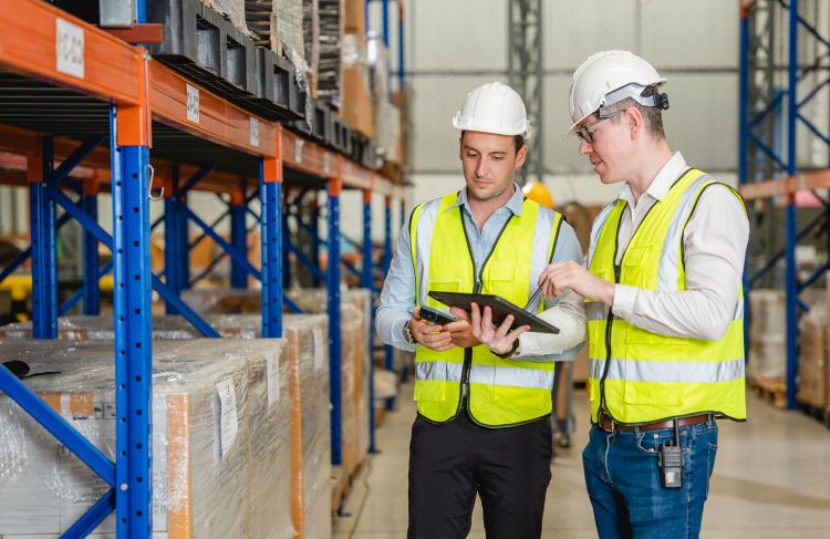 two people in warehouse looking at tablet and talking