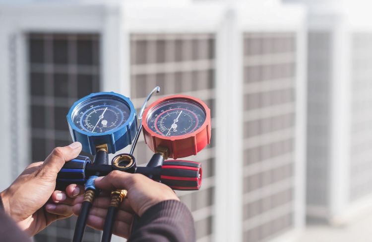 technician holding gauge testing air conditioner