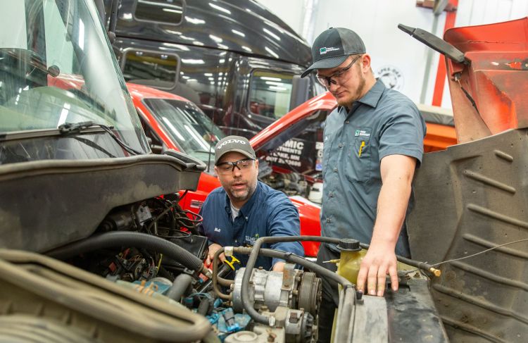 two people looking at air conditioning system in a heavy duty truck