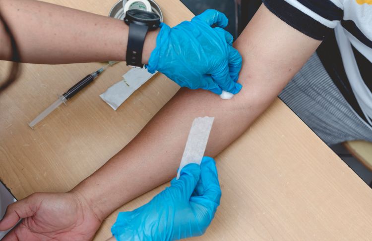 a person applying a bandage after taking a blood sample