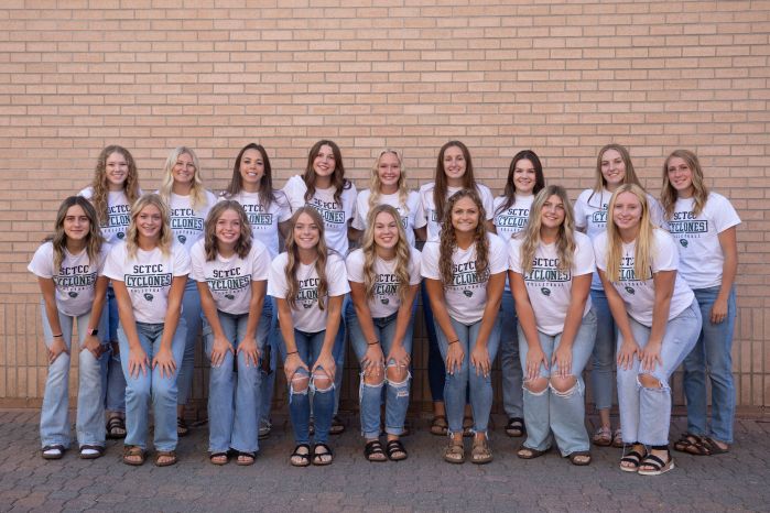 volleyball team in two rows against brick wall