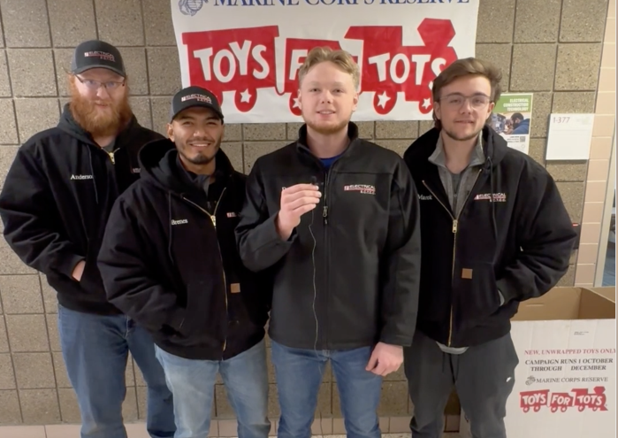 Mesa members in a row with Toys for Tots banner