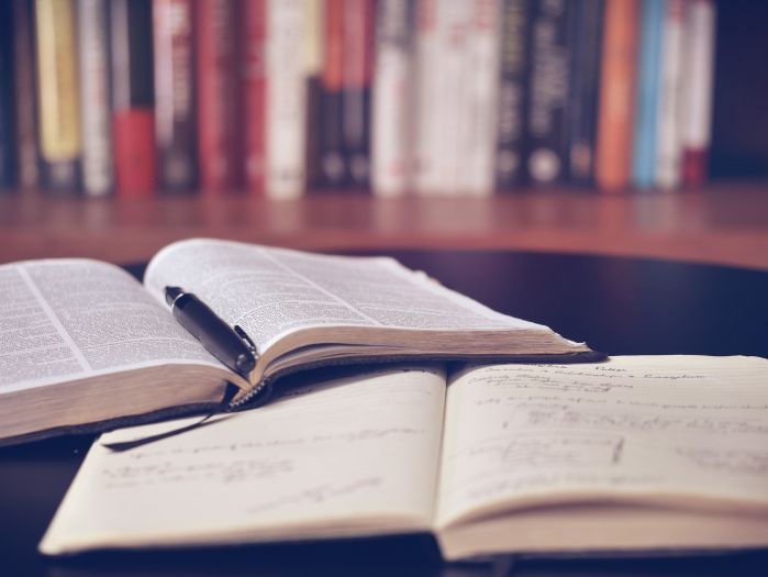 image of books in a library, two books are opening. One book for taking notes and the other for studying.