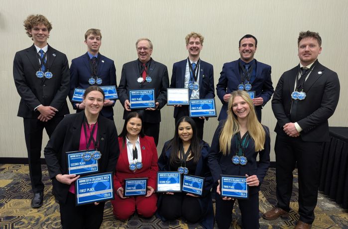 DECA students in two rows with medals and plaques