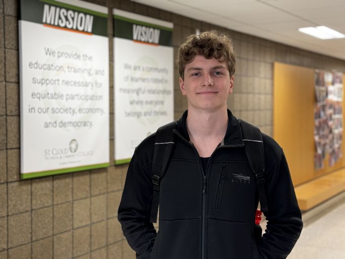 Micah Davis in front of mission and vision, smiling