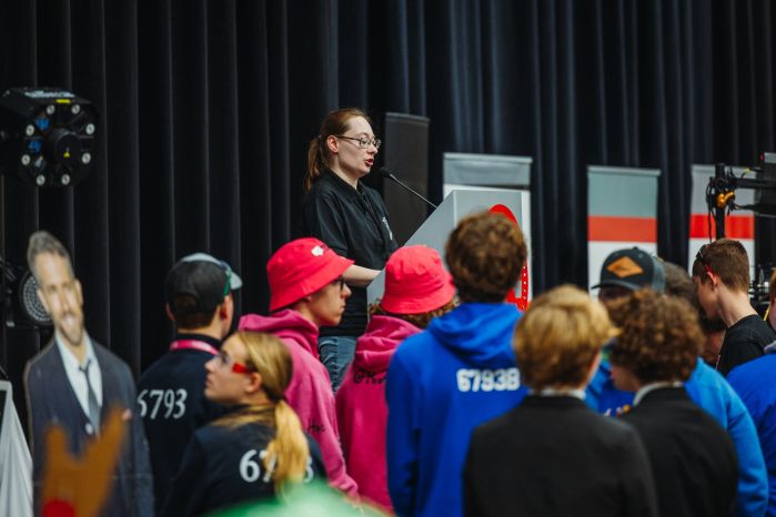 Katie Frank at a podium speaking to a crowd of folks at VEX