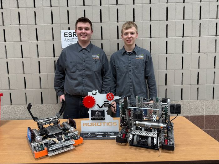 Two students with robots and award
