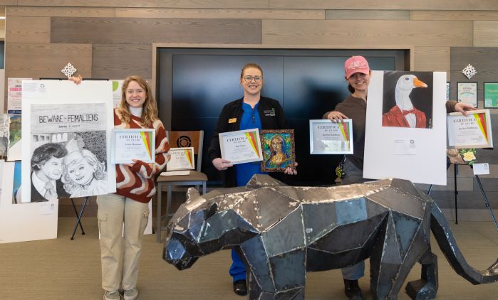 Three winners from art contest pose with art and certificates
