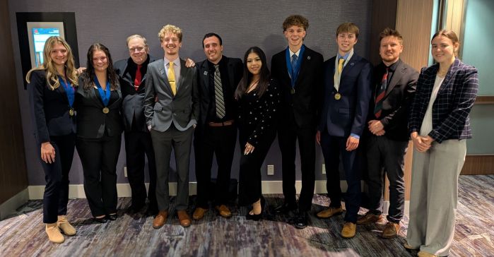 Group of 10 DECA students in a row, smiling at the camera.