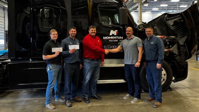 Tyler, Timmy, Jon, Daniel and Matt stand in front of a semi with the checks and shaking hands