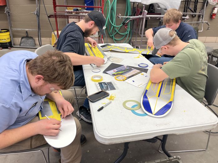 four auto body students working on designs for their skateboards