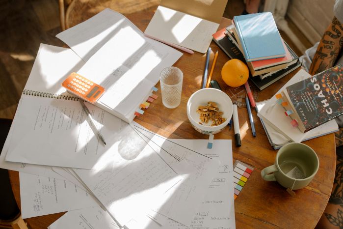 desk full of study supplies. Paper, snacks, books, &  computer 