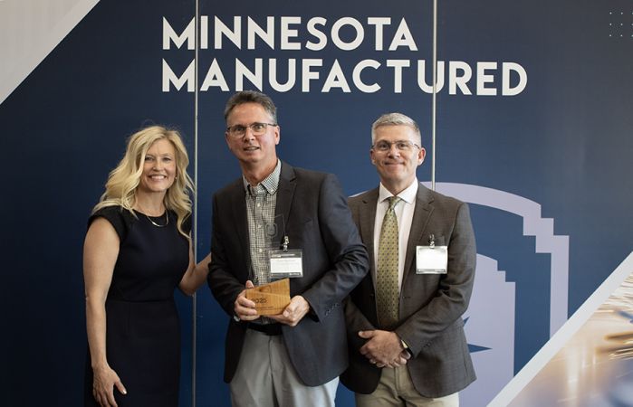 Steve Nusbaum with two others, holding his award and smiling at the camera