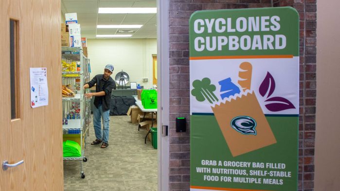A student worker puts food on shelves in the cupboard