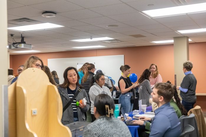full room with students talking to employers at tables