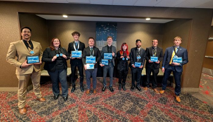 Nine DECA students in a row holding their awards