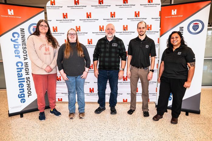 Brian Volkmuth in the middle with four other folks in front of an HTC backdrop
