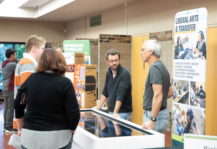 Two instructors chat with visitors at the open house