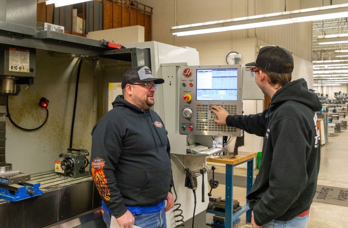 two CNC students work on the machine in the SCTCC lab